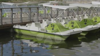 Green catamarans on the pier of a boat station