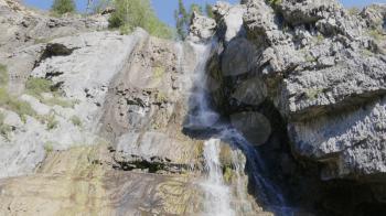 Big beautiful waterfall flows down the rocks mountains.