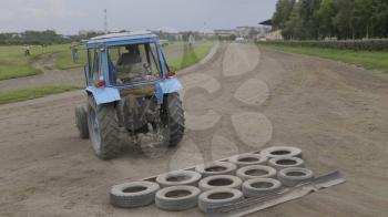 Wheeled tractor blue dub track racecourse old car tires.