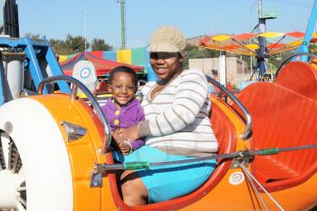 RUSTENBURG, SOUTH AFRICA - MAY 25: Black African mother and daughter enjoying airplane roundabout at Rustenburg Fair on May 25, 2014 in Rustenburg South Africa.   