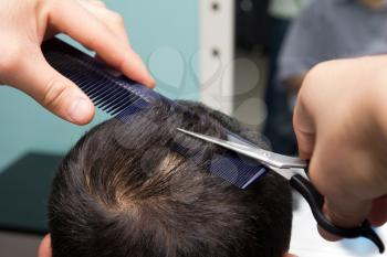 Professional hairdresser cutting childs hair in beauty saloon.