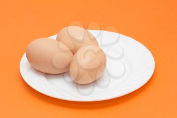 fresh eggs on a plate on the orange background