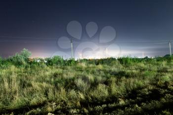 Electric poles in the field at night .