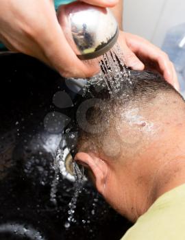 Washing the head of a man after a haircut in a beauty salon .