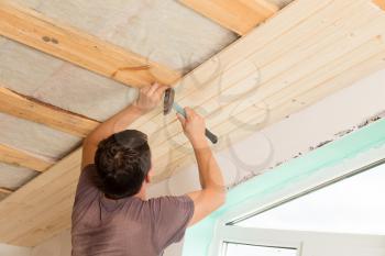 worker working on a wooden ceiling in the house .