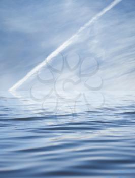 trace of the aircraft in the sky with reflection on water