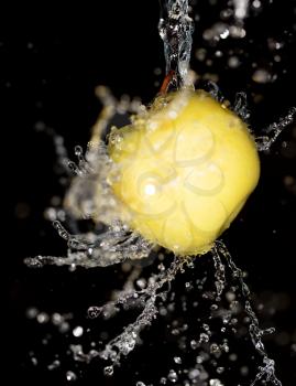 yellow apple in water on a black background