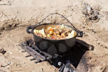 meat with potatoes in a cauldron on fire