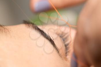 Grooming the eyebrows thread in a beauty salon. close