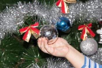 toy on the Christmas tree in a child's hand for the New Year