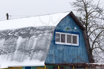 Snow on the roof of the house in the winter