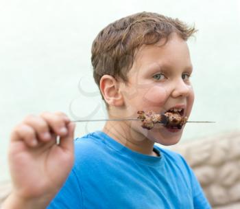 boy eats kebab on a stick