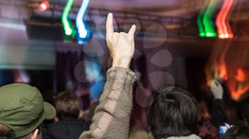 concert crowd in front with hands up with rock-n-roll sign