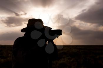 silhouette of a man with a camera on a sunset background