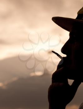 silhouette of a man smoking a cigarette on the sunset background