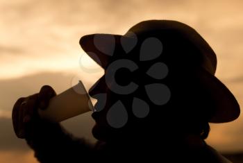 silhouette of a man drinking water on the sunset background