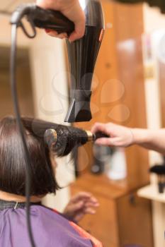 Styling female hair dryer in the beauty salon