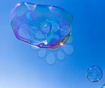 Big soap bubble against the blue sky .