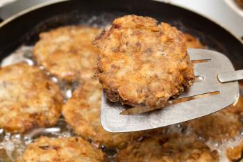 Meat patties are fried in a frying pan .