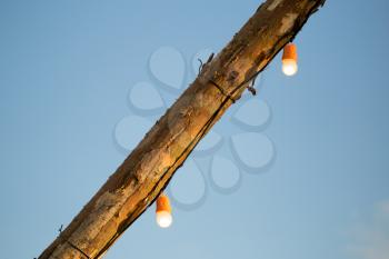 The bulb burns on a wooden pole .