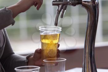 Barman pours beer into a plastic glass .