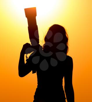 Silhouette of a girl photographer at sunset .