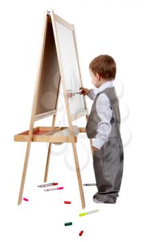 A child paints on an easel in the studio, isolate on white