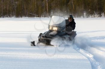  man riding a snowmobile on a background of forest