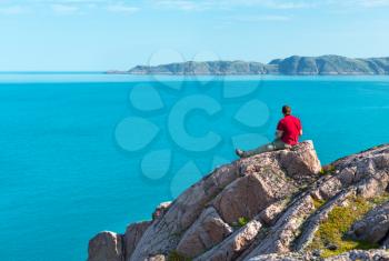 man sitting on a rock overlooking the sea