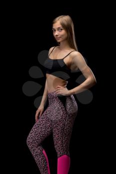 Fitness girl in passionate pose on black background