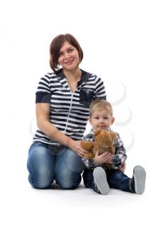 Young beautiful mother in blue jeans sitting with her son three years on the floor in the studio, isolate on white.