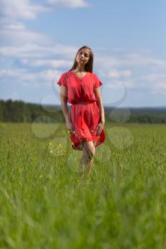Young pretty woman in red dress against blue sky.