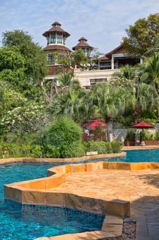 Outdoor swimming pool and wooden chairs in Thailand