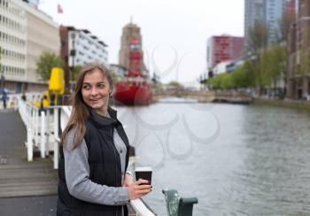 Portrait of a girl with a glass of coffee on a bridge in Rotterdam.