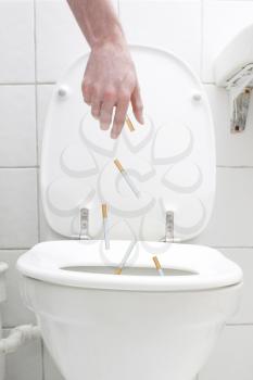 Royalty Free Photo of a Person Throwing Cigarettes in the Toilet