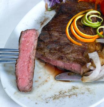 fresh juicy beef ribeye steak grilled with orange and lemon peel on top and vegetable beside