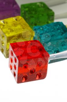 bounch of colorfull translucent dice shaped lollipops backlit on white background
