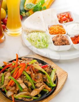 original fajita sizzling smoking hot served on iron plate ,with selection of beer and fresh vegetables on background ,MORE DELICIOUS FOOD ON PORTFOLIO