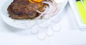 fresh juicy beef ribeye steak grilled with orange peel on top and onion beside