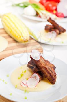 traditional Italian roasted pork ribs served on polenta bed,corn cream