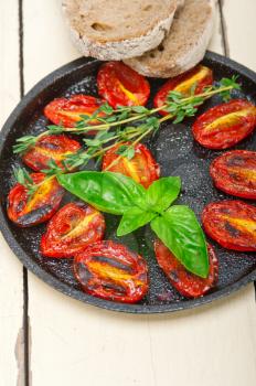 oven baked cherry tomatoes with basil and  thyme on a cast iron skillet 