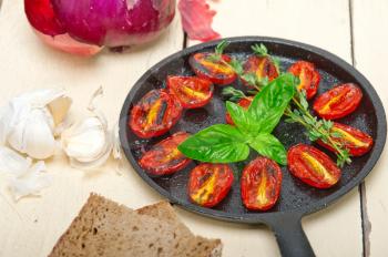 oven baked cherry tomatoes with basil and thyme on a cast iron skillet