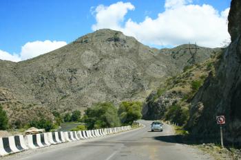 Royalty Free Photo of a Car Driving by a Mountain
