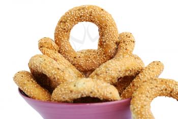 Round rusks with sesame seeads in pink bowl isolated on white background.
