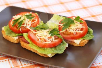 Sandwiches with bacon, lettuce, tomato and cheese on plate.