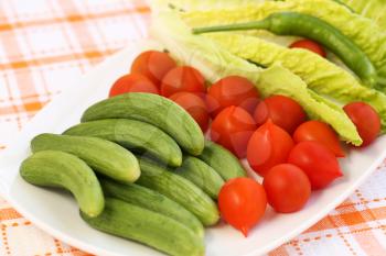 Fresh vegetables on white plate on table.