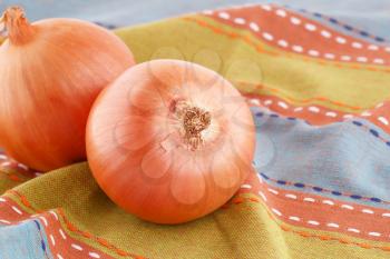 Two onions on colorful towel.