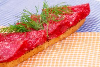Sandwich with salami and dill isolated on kitchen towels.