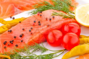 Salmon fillet with lemon, dill, pepper, tomatoes on plate.