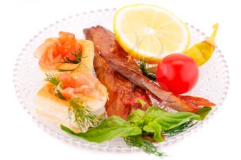 Smoked fish with fresh vegetables and lemon on plate isolated on white background.